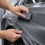 車体の曲面へラッピングフィルムをスキージーで押さえている様子