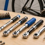 ロードバイクのそばに複数のトルクレンチと整備用ビットを並べた作業台