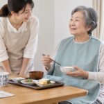 食事エプロンを着けて食事をする高齢者と見守る介助者