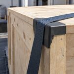 木箱の角に保護具を挟んで荷締めベルトを掛けた様子