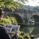 石造アーチ橋を眺めながら写真入りの本を開く人