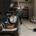 ガレージで長期保管中の旧車に維持充電器を接続している様子
