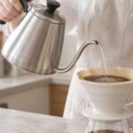細口のドリップポットからコーヒーへお湯を注いでいる様子