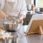 料理教室の調理台でレシピスタンドを見ながら調理する講師