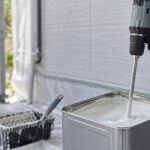 開いた一斗缶の塗料をコードレスかくはん機で混ぜている様子