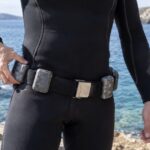 海辺でダイビング用ウェイトベルトの装着具合を確かめるダイバー