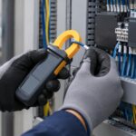 制御盤の配線をクランプメーターで測定している作業イメージ