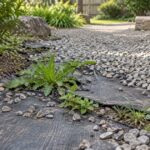 砂利の下で露出した防草シートから雑草が生えている庭の様子