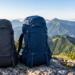 山の岩場に容量の異なる大型登山用バックパックを2つ並べたイメージ