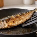 フライパンの焼き魚を幅広ターナーで支えている様子