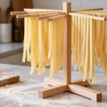 木製ラックに手作りの平打ちパスタを掛けているキッチンの様子