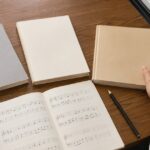 無地の音楽書と楽譜を鍵盤のそばで比較している様子