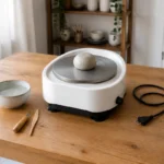 自宅の木製テーブルに置かれた小型電動ろくろと粘土