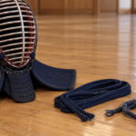 道場の床に剣道の面と新品・使用済みの紺色の面紐を並べた様子