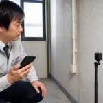 壁面点検でスマートフォンと離して小型センサーを設置する作業員
