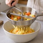 手動式ムーランで加熱した野菜を裏ごししている様子