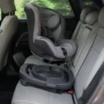 車の後部座席で回転ベースにチャイルドシートを合わせている様子
