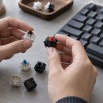 メカニカルキーボードの横で複数のキースイッチを比較する手元