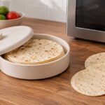 電子レンジの横にトルティーヤ入りの保温容器と大きさの異なる生地を並べた様子