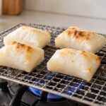 ガスコンロ上の焼き網で4個の餅を焼いている様子