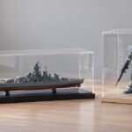 横長の艦船模型と背の高いロボット模型を透明ケースに展示した様子