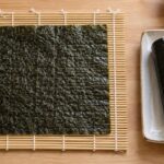 竹製の巻きすに海苔を広げ、完成した海苔巻きを添えた調理風景
