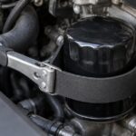 エンジンルームのオイルフィルターにベルトレンチを掛けた様子
