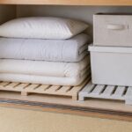 押し入れの床に木製と樹脂製のすのこを敷き、布団や収納箱を載せた様子
