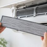 エアコンの前で交換用フィルターを手に持っている様子