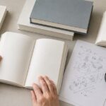複数の本と技術資料を机上で調べている様子