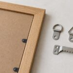 木製額の裏側に複数形状の吊り金具を並べたイメージ