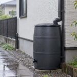 雨の日の住宅脇に雨どいと雨水タンクが設置された様子