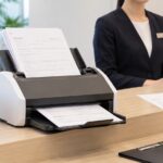 受付カウンターで書類をスキャナーに通して電子化している様子