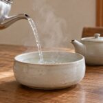 熱湯を広く低い陶器へ注ぎ、煎茶用に冷ましている様子