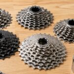 複数の自転車用カセットスプロケットとフリーハブ、チェーンが作業台に並んでいる様子