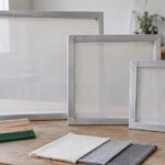 大きさの異なるシルクスクリーン用アルミ枠とスキージを並べた作業台