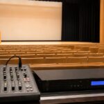小規模ホールの客席後方に音響ミキサーと再生機器が設置されている様子