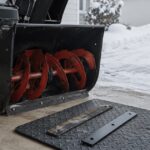 雪の残る車庫で除雪機と新旧のスクレーパーを並べた様子