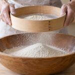 木枠の粉ふるいでそば粉をふるっている様子