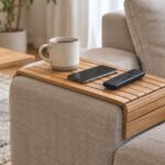 ソファの肘掛けに木製トレイを載せ、カップやスマホを置いた様子