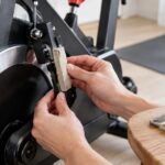 スピンバイクのフライホイール付近でフェルト製ブレーキパッドを交換している様子