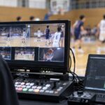 体育館で複数カメラの映像を確認しながらスポーツ配信を行う様子