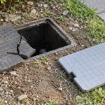 地面の散水栓ボックスと割れたふた、交換用のふたが並ぶ様子