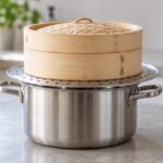 鍋と竹せいろの間に円形の蒸し板を置いた様子