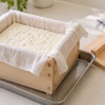 布を敷いた木製の豆腐型で豆腐を成形している様子