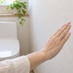 トイレの壁に設置した擬音装置へ手をかざしている様子