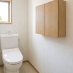 狭いトイレの壁に木製収納キャビネットを設置した室内イメージ