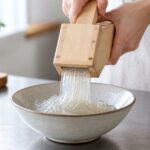 木製のところてん突きから器へところてんを押し出す様子
