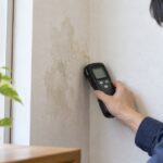 室内の壁に水分計を当てて湿気を測定している様子