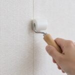 壁紙の継ぎ目を小型ローラーで押さえている様子